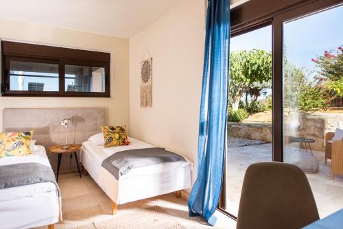 1 dormitorio con 2 camas y ventana en Magnifique villa avec piscine au bord de mer, en Chorafakia