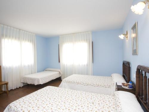a blue room with three beds and two windows at Hotel Rural Suquin in Navia