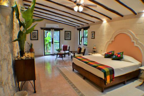 a bedroom with a bed and a living room at Hacienda Chichen Resort and Yaxkin Spa in Chichén-Itzá