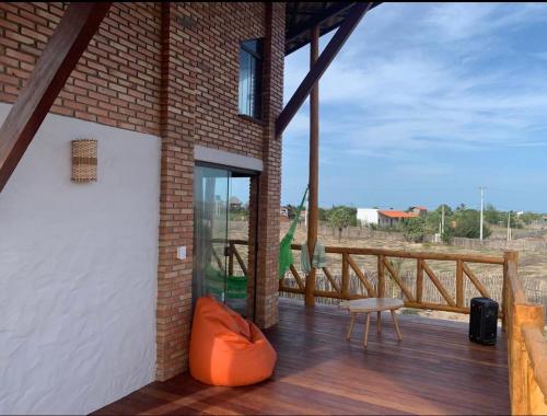 a wooden deck with a glass door and a chair at Chalé MACAPAZ in Luis Correia