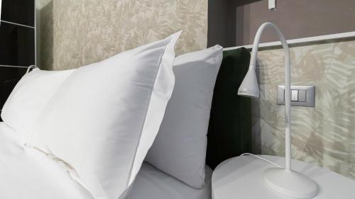 uma cama com almofadas brancas e um candeeiro em Italianway - The B Village New em Milão