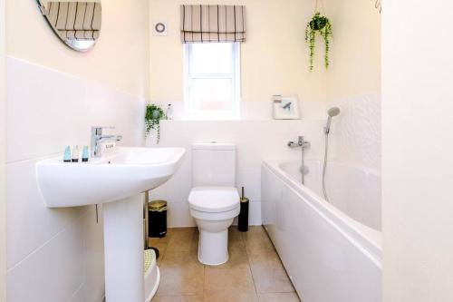 a white bathroom with a toilet and a sink at Luxury detached home in 168 Upton Grange in Mollington