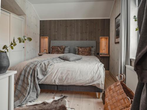 Tväråstugan في آرا: غرفة نوم بسرير وجدران خشبية