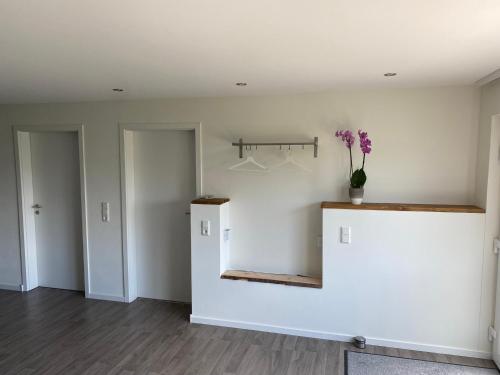 a room with white walls and a counter with a vase of flowers at Ferienwohnung Maldener in Namborn