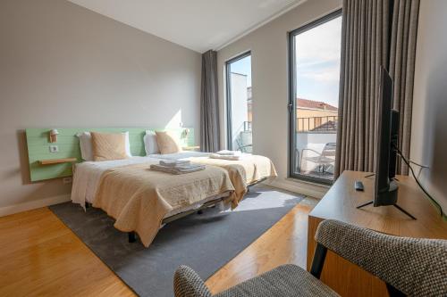a bedroom with a bed and a tv and a balcony at Oporto Trendy Formosa in Porto