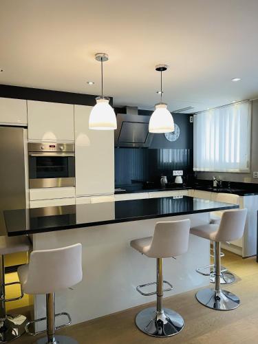 une cuisine avec des placards noirs et blancs et des tabourets de bar dans l'établissement Magnifique Modern appartement avec terrasse FERN12, à Cannes