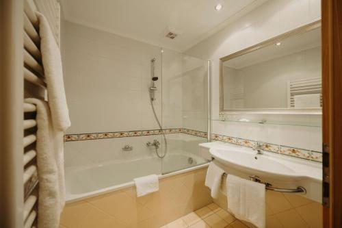 a bathroom with a tub and a sink and a bath tub at Hotel Lerch in Sankt Johann im Pongau