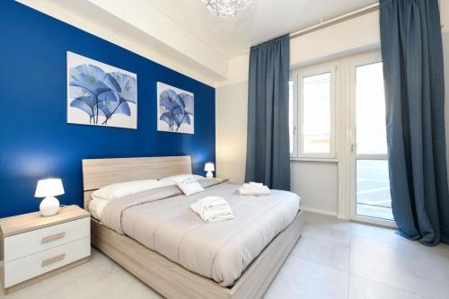 My Desenzano Family Apartment في ديسينسانو ديل غاردا: غرفة نوم بسرير كبير بجدران زرقاء