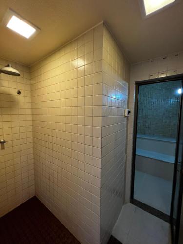 La salle de bains est pourvue de murs carrelés blancs et d'une douche. dans l'établissement Apto 305 - Praia Grande Residence, à Arraial do Cabo