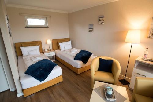 a hotel room with two beds and a chair at Pension Luuward 3 Sterne Hotel in Wenningstedt