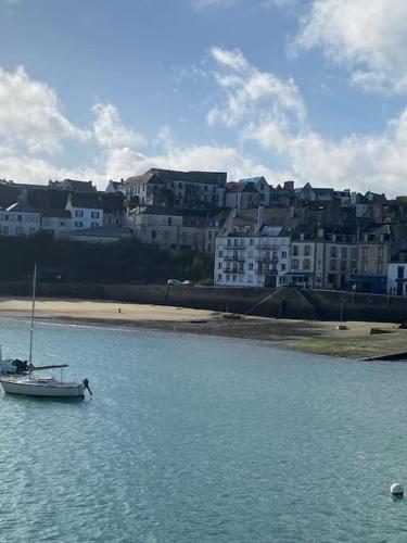 a sail boat in the water near a beach at Charmant petit appartement les pieds dans l'eau in Douarnenez