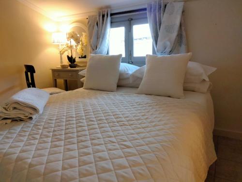 uma cama branca com almofadas brancas e uma janela em Les Penyetes Boutique Bed and Breakfast em Campell