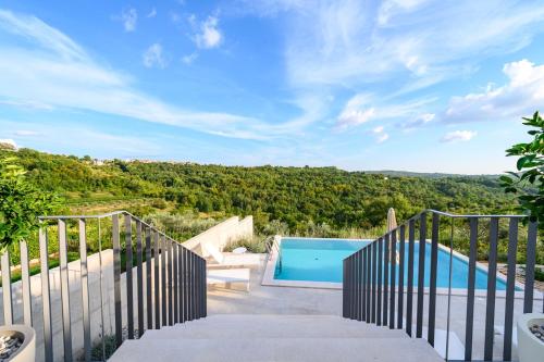 a villa with a swimming pool and a balcony at Villa Volare Cantare with 2 br, a heated pool and panoramic view near Buje, Istra in Momjan