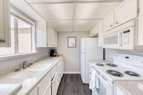 a white kitchen with a sink and a refrigerator at Lovely 2 bedroom condo in quiet location in Fresno