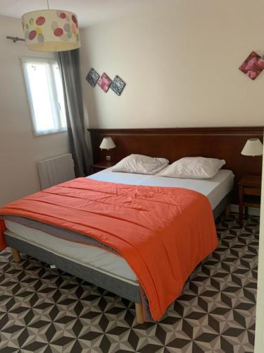 a bedroom with a bed with a red blanket at Les Gîtes de la Colo in Ravenoville