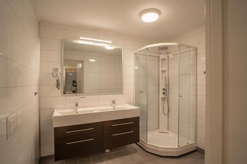 a bathroom with a sink and a shower with a mirror at Amazing and secluded northern light apartment near sea and city! in Selnes
