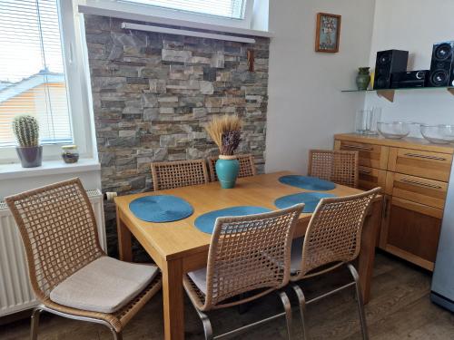 a dining room table with chairs and a stone wall at Apartmán Rubicon in Poprad