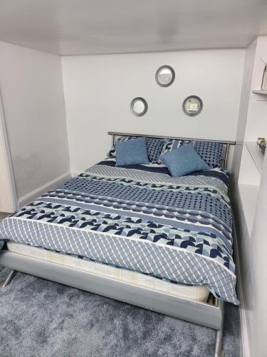 a bed with blue pillows on it in a room at Homey Flat in Tooting in London