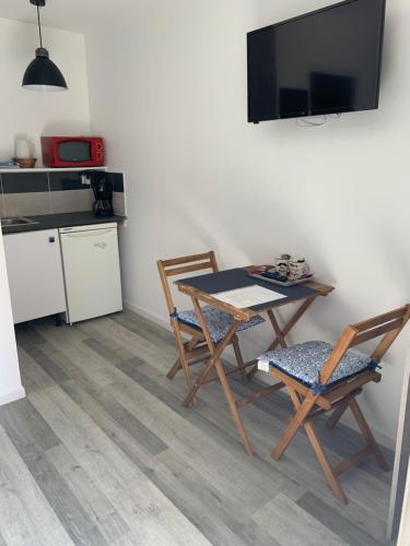 a kitchen with a table and two chairs and a television at Les Gîtes de la Colo in Ravenoville