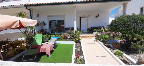 a patio with a lawn with chairs and an umbrella at Casa da Cândida in Nazaré