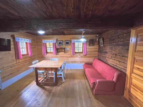 sala de estar con mesa y sofá rojo en Eco tourist farm Mikl, en Prevalje