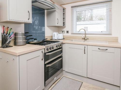 a kitchen with white cabinets and a stove and sink at Balmoral in Pendine