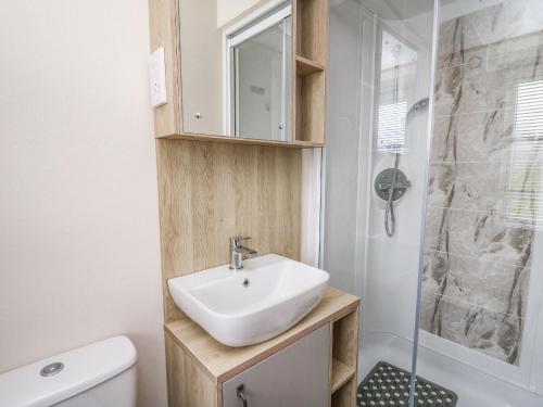 La salle de bains est pourvue d'un lavabo et d'une douche. dans l'établissement Balmoral, à Pendine