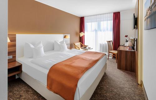 a hotel room with a large bed and a desk at PLAZA INN Regensburg in Regensburg