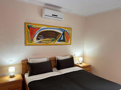 1 dormitorio con 1 cama y una pintura en la pared en Villa Sanchez in Strandnähe mit Pool, Jacuzzi, Klima, WiFi, Gas BBQ, en Santanyí