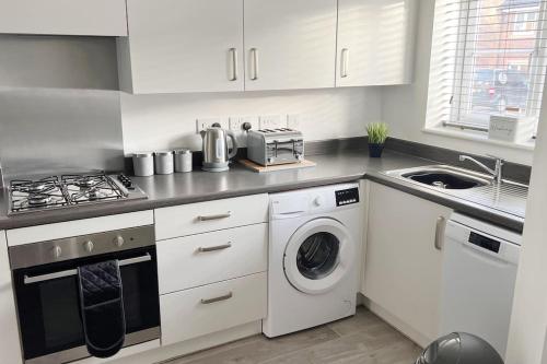 a kitchen with a stove and a washer and dryer at Kingfisher House by Blue Skies Stays in Stockton-on-Tees