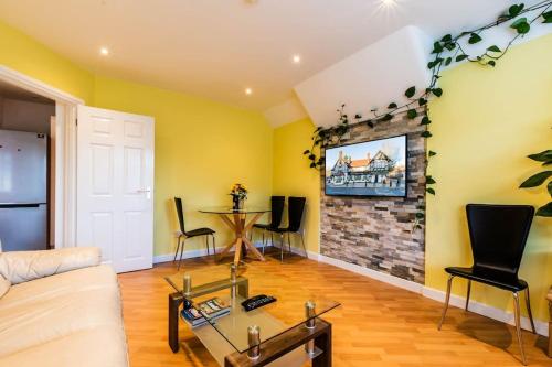 a living room with a couch and a tv on a wall at Comfy Apartment 16 Easy access to Central London in Tadworth