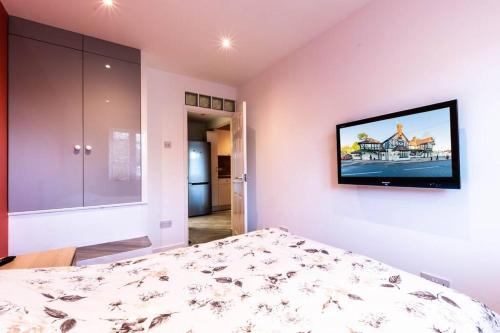 a bedroom with a bed and a tv on the wall at Comfy Apartment 16 Easy access to Central London in Tadworth