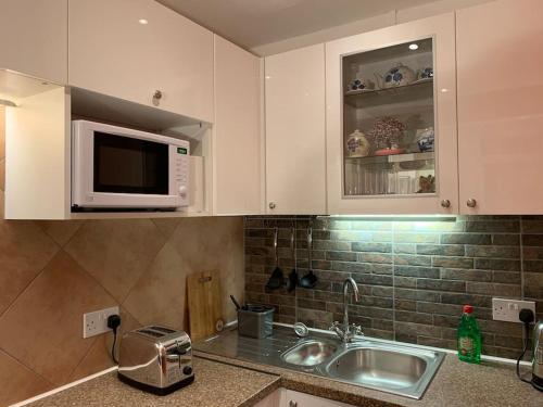 a kitchen with a sink and a microwave at Comfy Apartment 16 Easy access to Central London in Tadworth