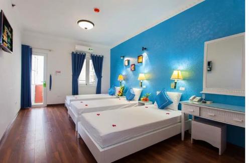 a room with three beds and a blue wall at Hanoi Jade Hostel in Hanoi
