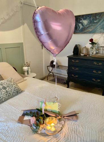 a heart balloon and a plate of food on a bed at Majoliebriarde B&B - Chambre d hôtes proche Disneyland et Paris in Saint-Germain-sur-Morin