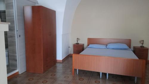 a bedroom with a bed and a wooden cabinet at CASA DELLE PEONIE in Ruffano