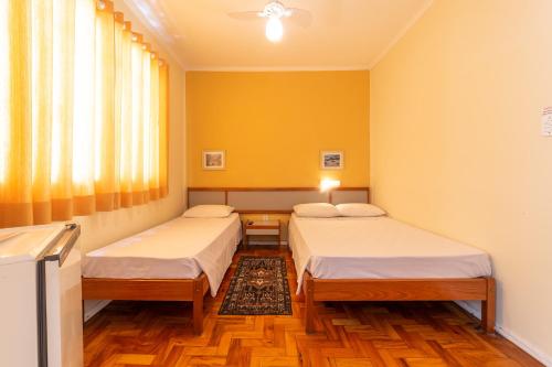 Duas camas num quarto com paredes amarelas em Hotel Solaris em São Lourenço