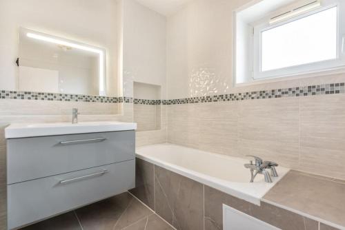 une salle de bain blanche avec une baignoire et un lavabo dans l'établissement Appartement luxueux vue Tour Eiffel - Defense, à Puteaux