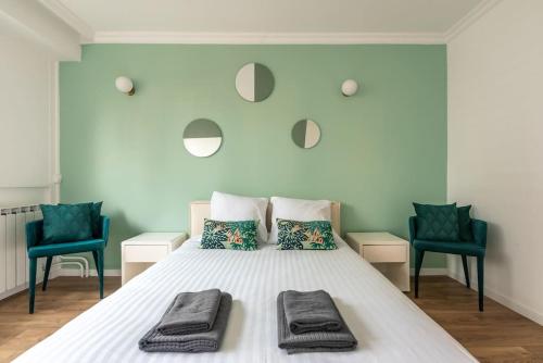 - une chambre avec un grand lit blanc et 2 chaises bleues dans l'établissement Appartement luxueux vue Tour Eiffel - Defense, à Puteaux