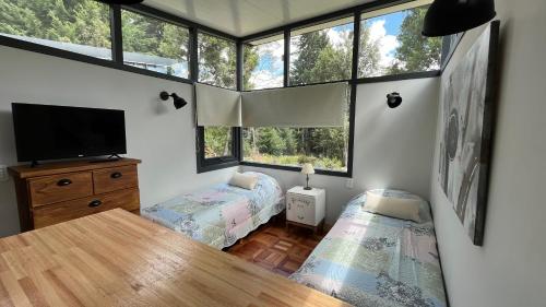 Habitación con 2 camas, TV y ventanas. en La Clarita en Villa La Angostura