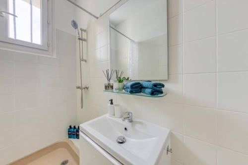 La salle de bains blanche est pourvue d'un lavabo et d'une douche. dans l'établissement Oh Parisien - 10 min Paris Montparnasse, à Vanves