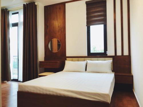 a bedroom with a bed with white sheets and two windows at Đức Tuân 2 Motel in Hai Phong