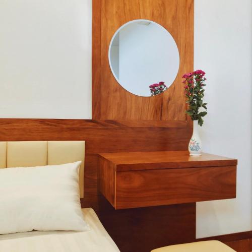 a bedroom with a mirror and a bed and a vase with flowers at Đức Tuân 2 Motel in Hai Phong
