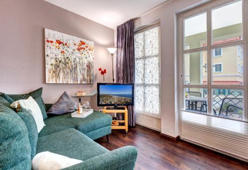 班辛海的住宿－Villa Margot - FeWo 02，客厅配有绿色沙发和电视
