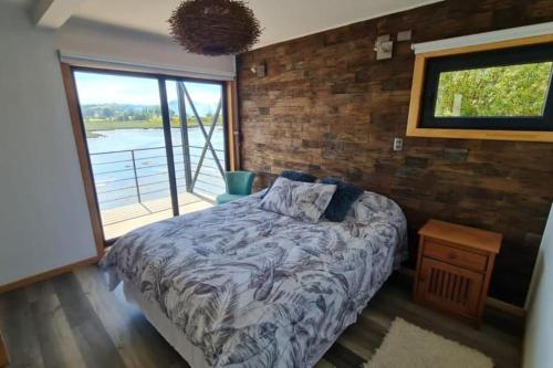 1 dormitorio con cama y pared de ladrillo en Departamento con vista al mar en Castro