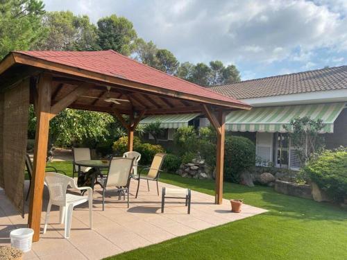 a wooden pavilion with chairs and a table in a yard at Villa Òdena in Odena