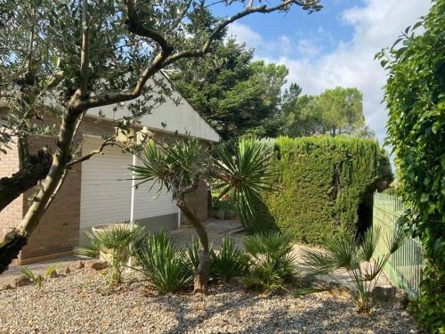 a garden with a hedge and a garage at Villa Òdena in Odena