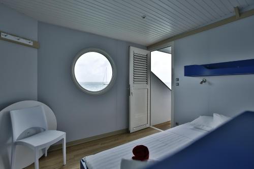 um quarto com uma cama, uma janela e uma cadeira em Aqualodge, Les Saintes, Terre de Haut em Terre-de-Haut