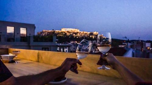 dos personas sosteniendo copas de vino en un balcón en Mosaikon Glostel en Athens