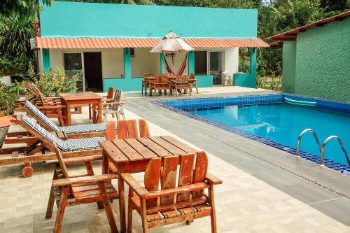 a resort with a swimming pool with tables and chairs at Ajubá Pousada in Morro de São Paulo
